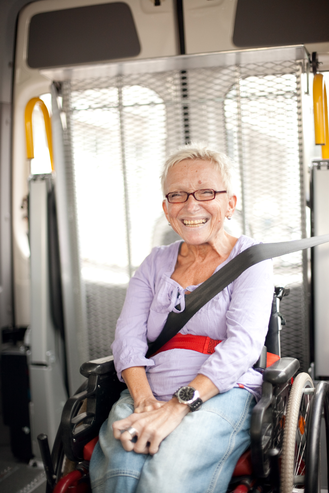Blick in ein Farhdienstfahrzeug. Eine Dame sitzt angeschnallt im Rollstuhl.